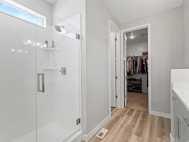 Spacious shower enclosure with clear glass door, brushed nickel hardware, and built-in shelving