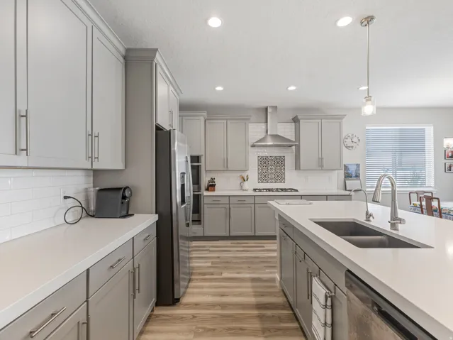 Modern kitchen featuring light gray cabinetry, white countertops, and wood-finish flooring