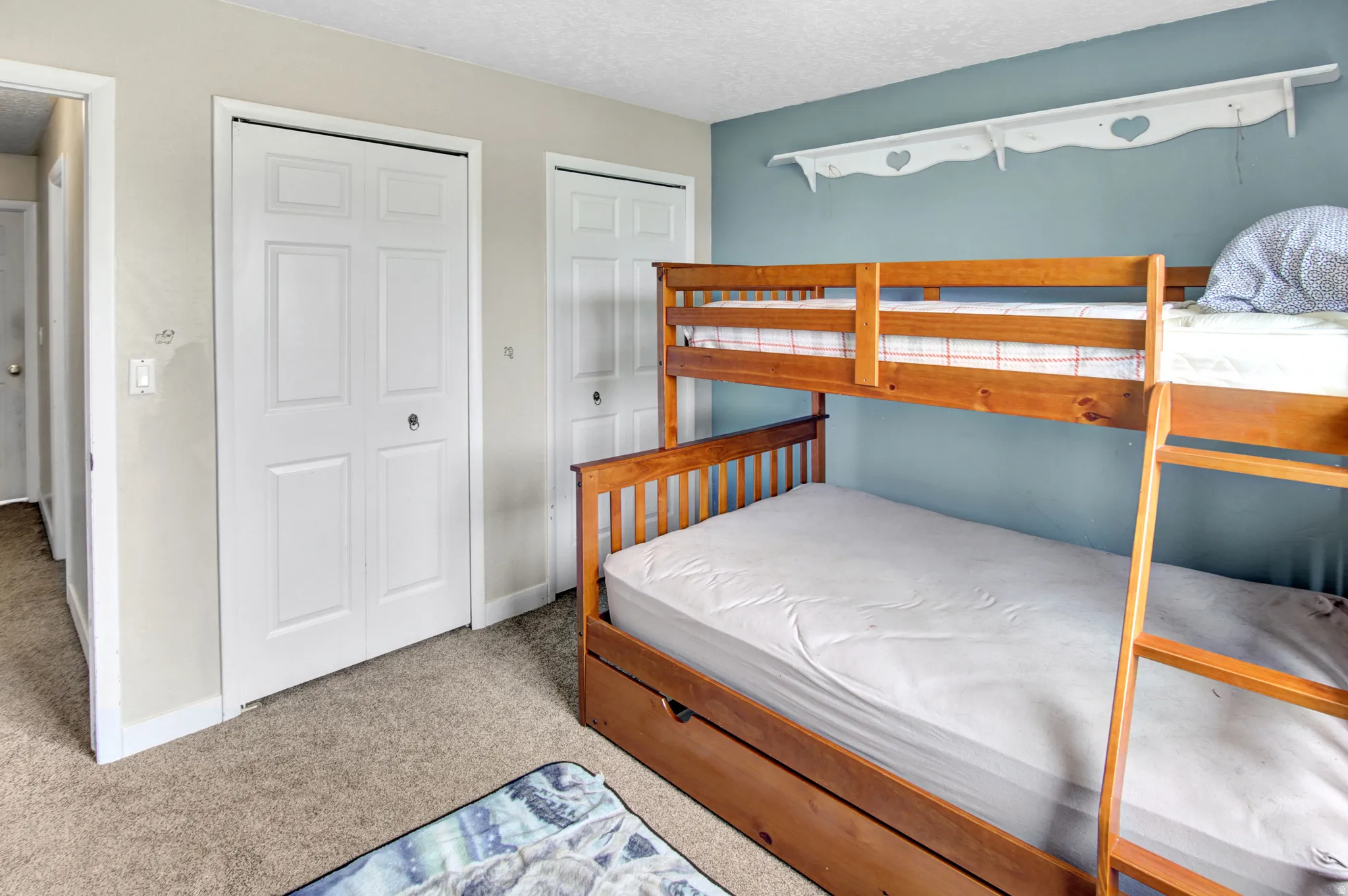 Carpeted room featuring multiple panel doors, a built-in wall shelf, and a light blue accent wall
