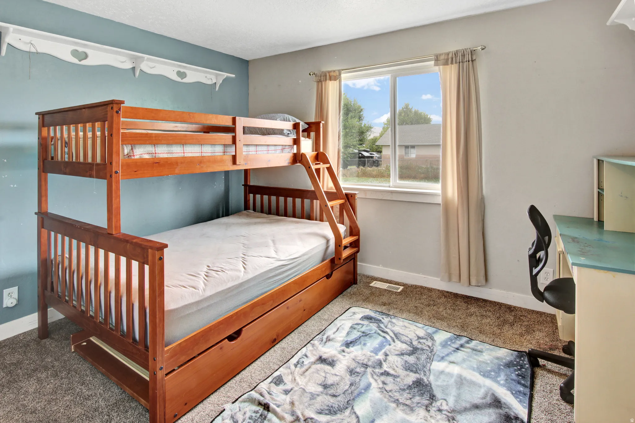 Carpeted room with a double-pane window, featuring a light blue accent wall and a white wall shelf