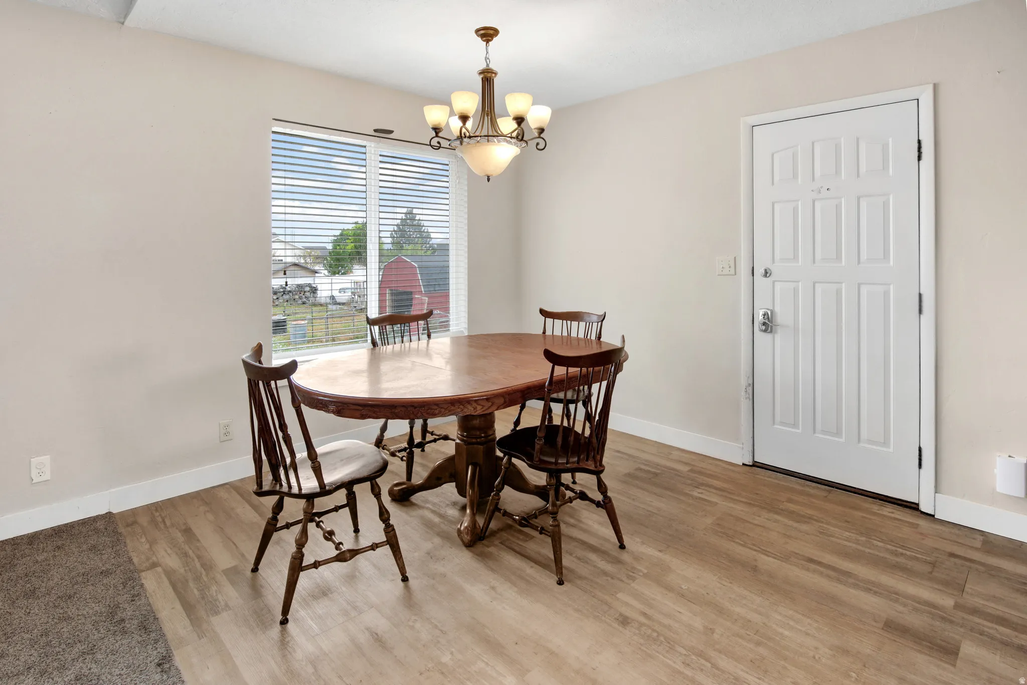Wood-finish flooring, white paneled door, and a multi-light chandelier