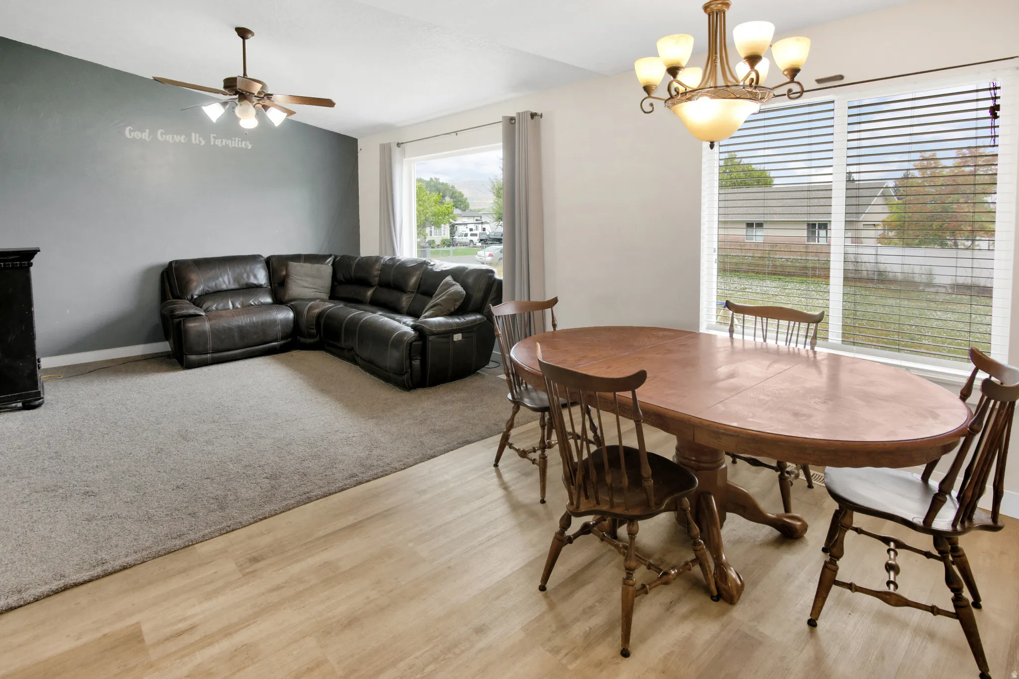 Expansive living area featuring wood-finish flooring, a ceiling fan, and large windows
