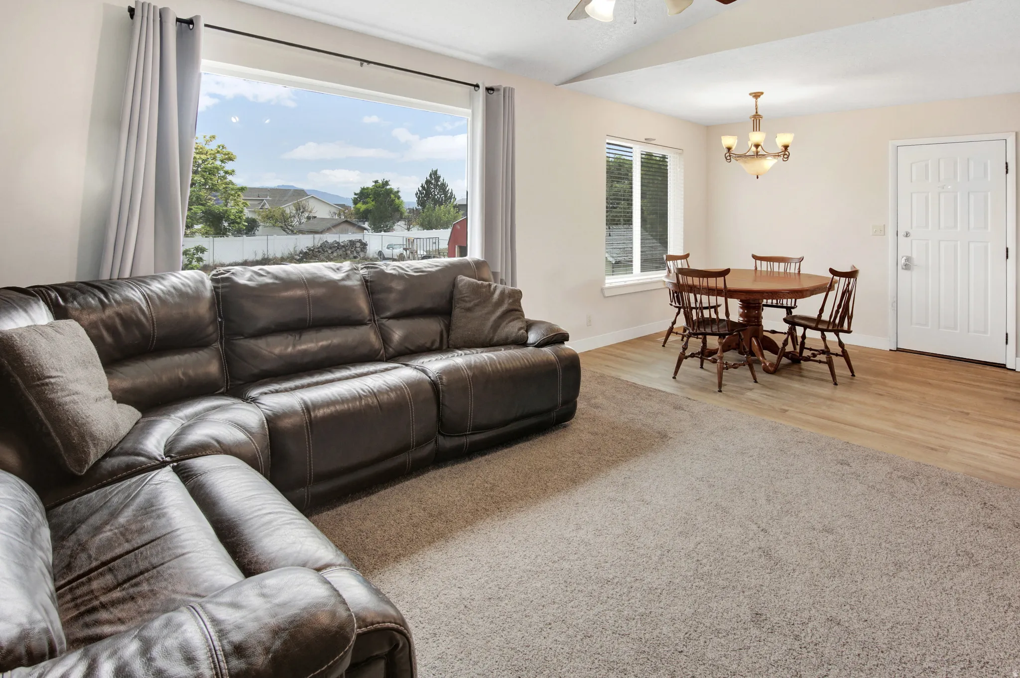 Expansive window, vaulted ceiling, wood-finish flooring, recessed lighting, and a front entry door