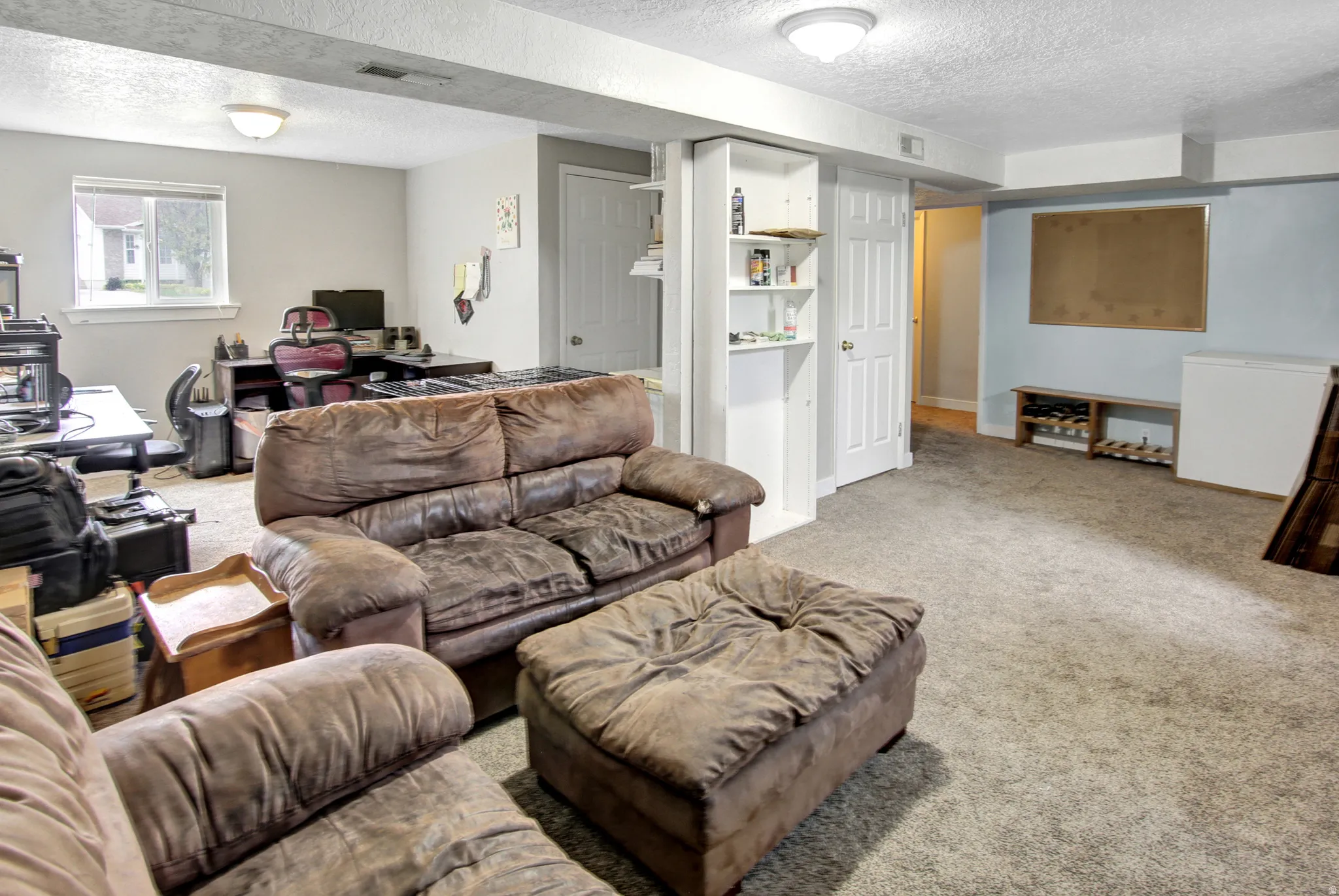 Expansive carpeted area featuring built-in shelving, recessed lighting, and a window