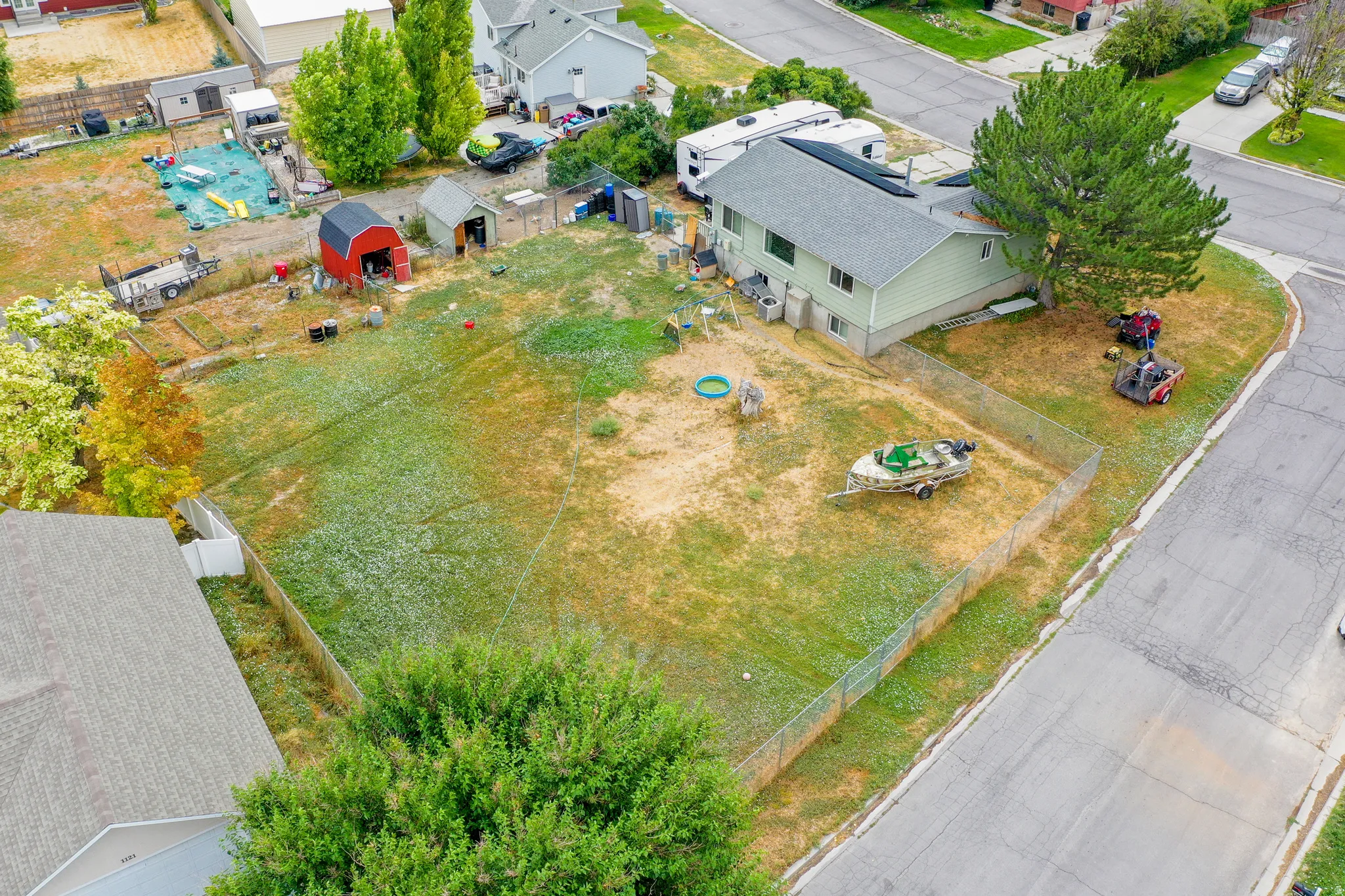 Expansive fenced yard with a detached storage shed and a secondary red-painted storage shed