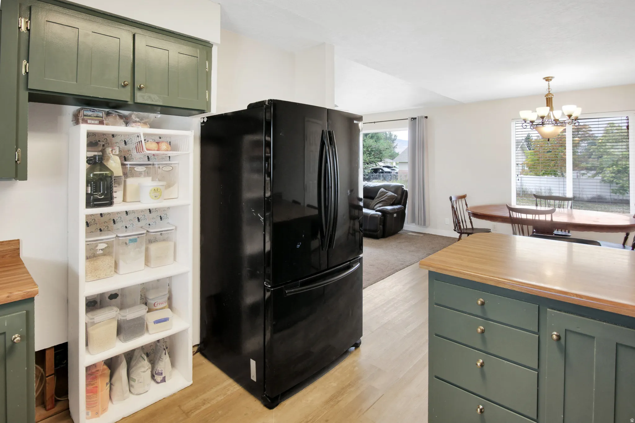 Wood-finish flooring with green cabinetry and light countertops