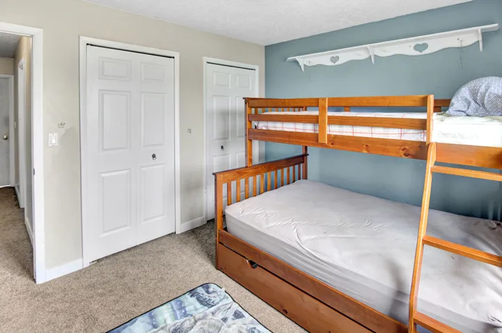 Carpeted room featuring multiple panel doors, a built-in wall shelf, and a light blue accent wall