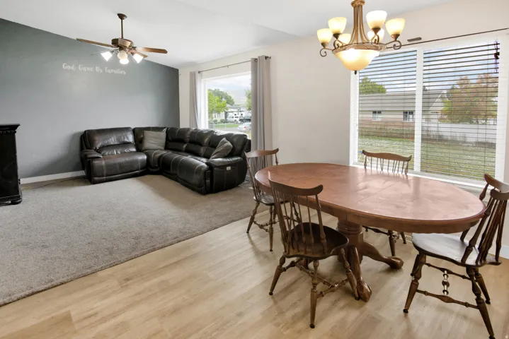 Expansive living area featuring wood-finish flooring, a ceiling fan, and large windows