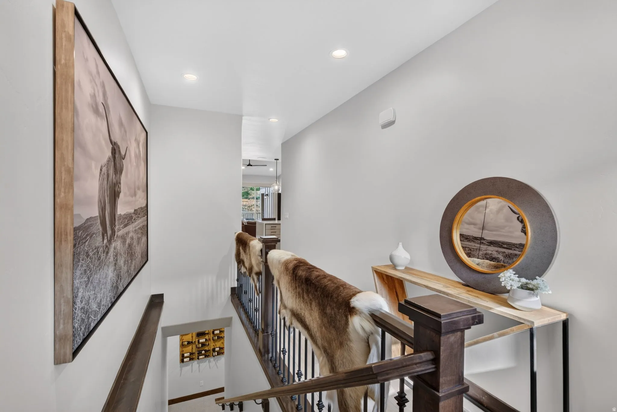 Hardwood stair railing with decorative metal balusters, recessed ceiling lighting, and light gray wall finish