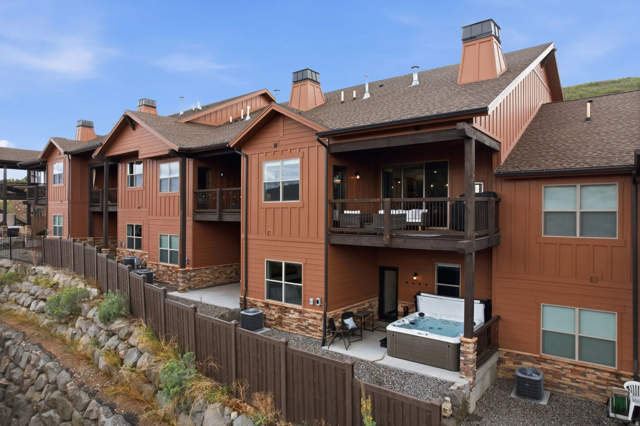 Multi-level residential exterior with wood siding and stone veneer accents