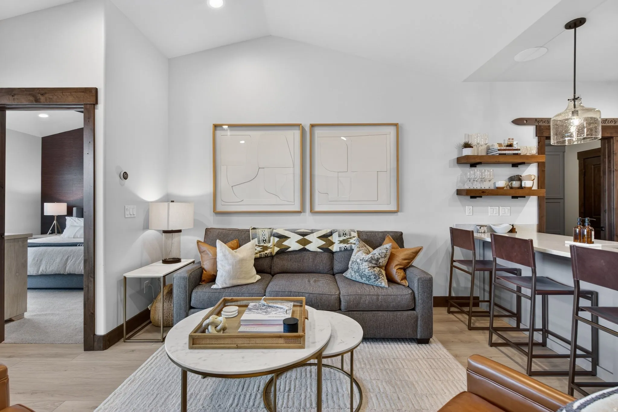 Vaulted ceiling, recessed lighting, wood-finish flooring, built-in shelving, and a bar counter with seating