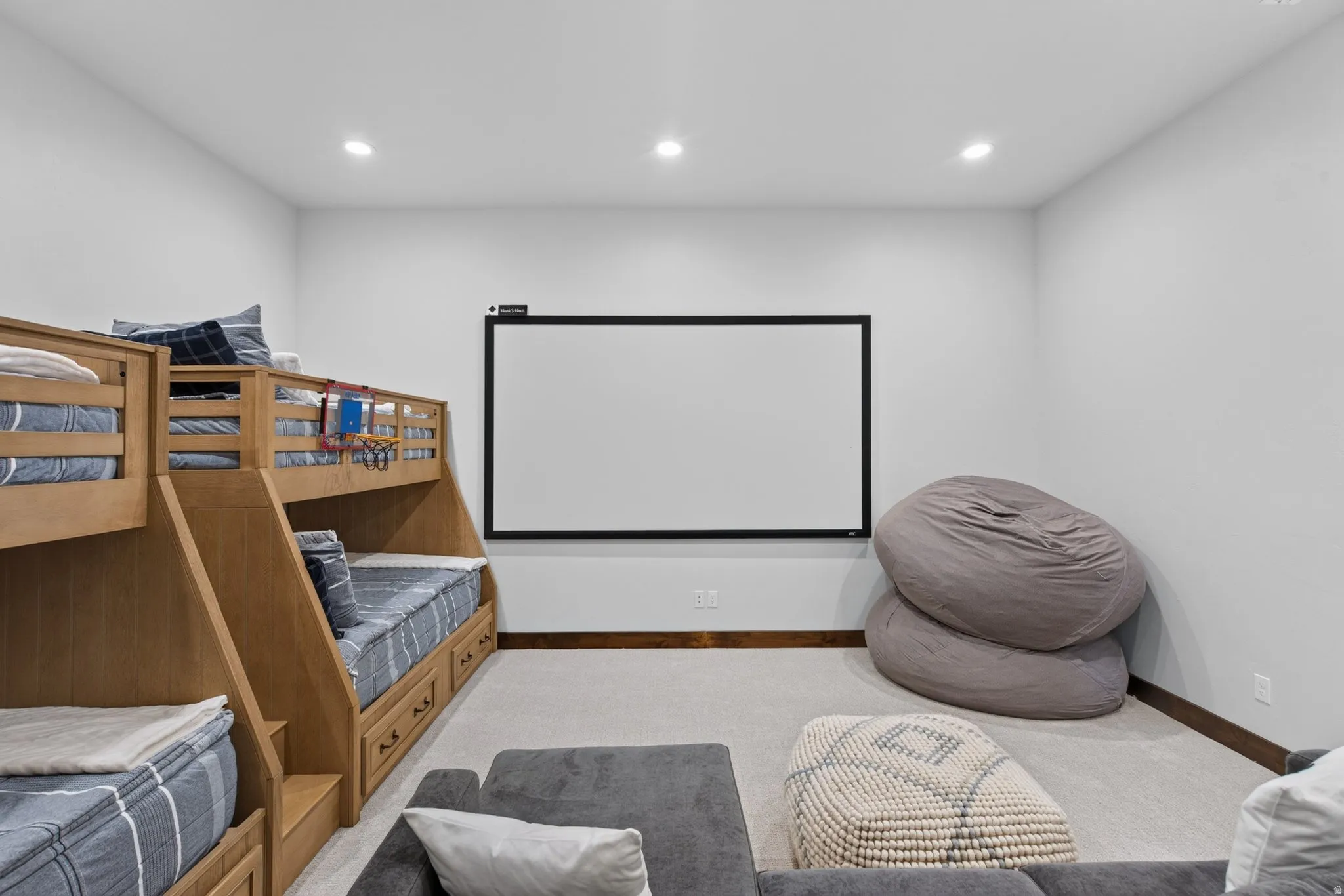 Recessed lighting illuminates the carpeted floor and built-in bunk beds with integrated storage drawers