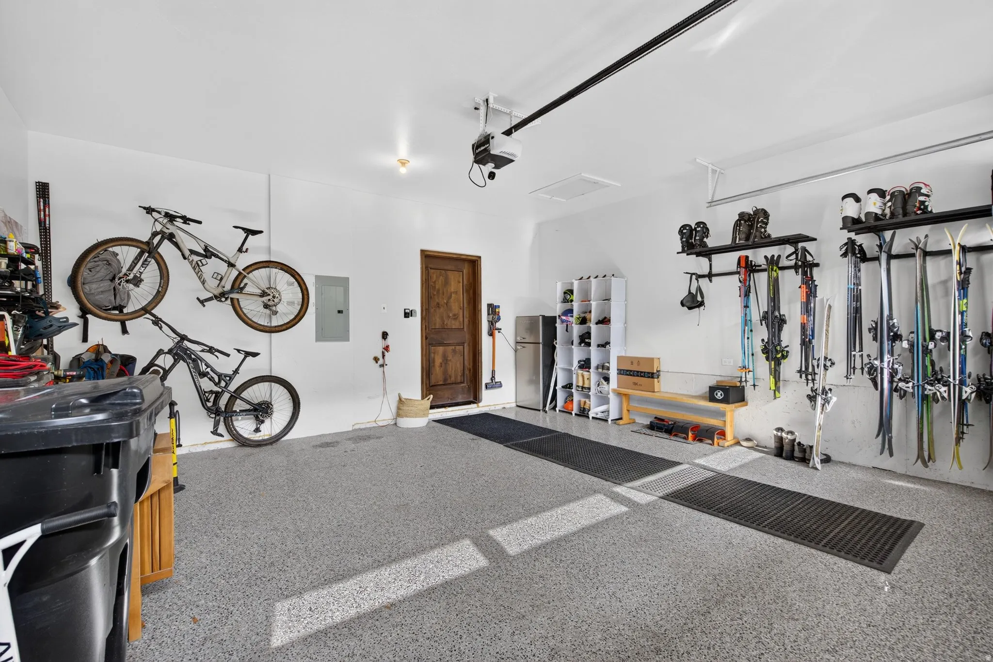 Garage with light gray epoxy flooring, white walls, and a wooden entry door
