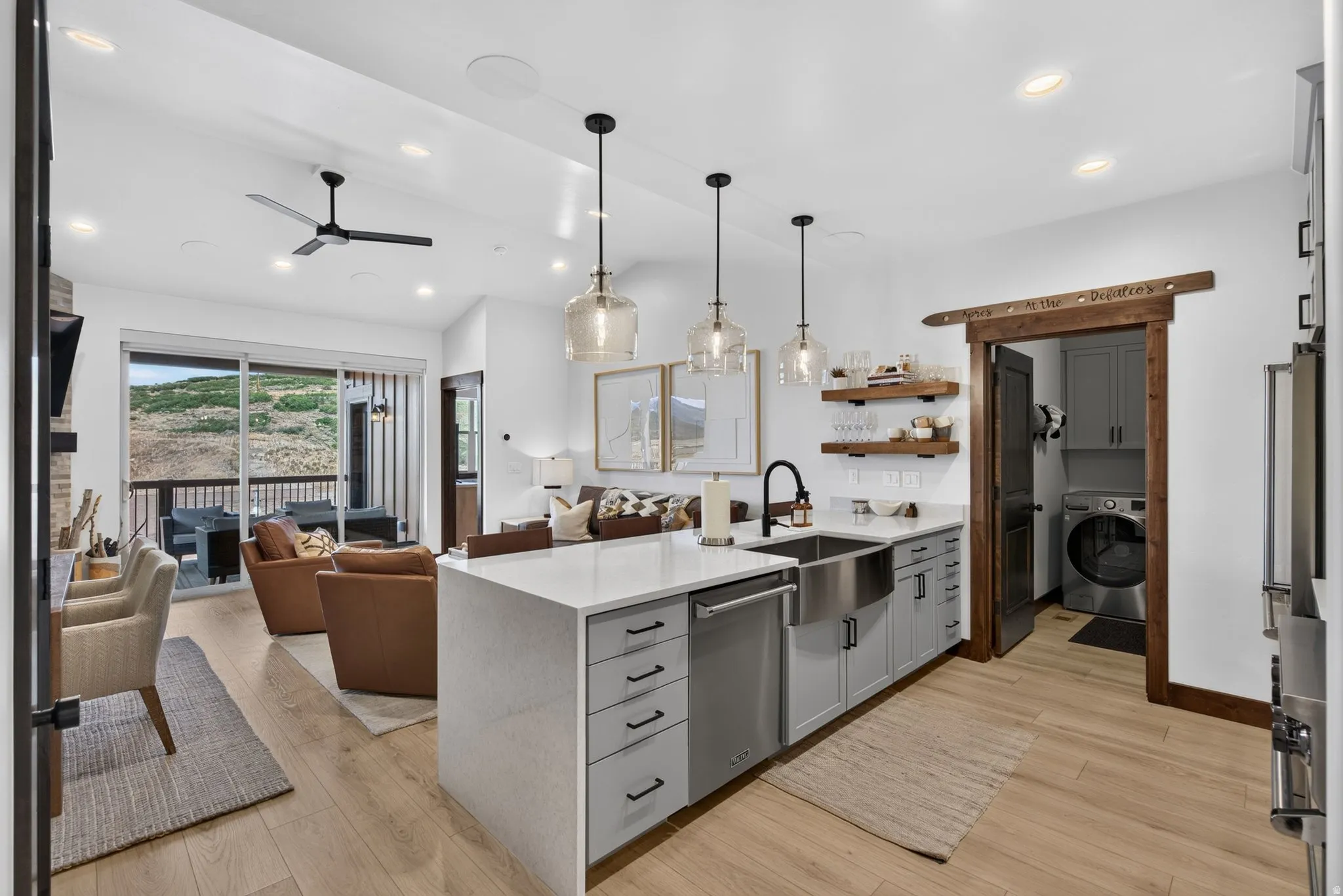 Modern kitchen island with a white countertop, farmhouse sink, and gray cabinetry