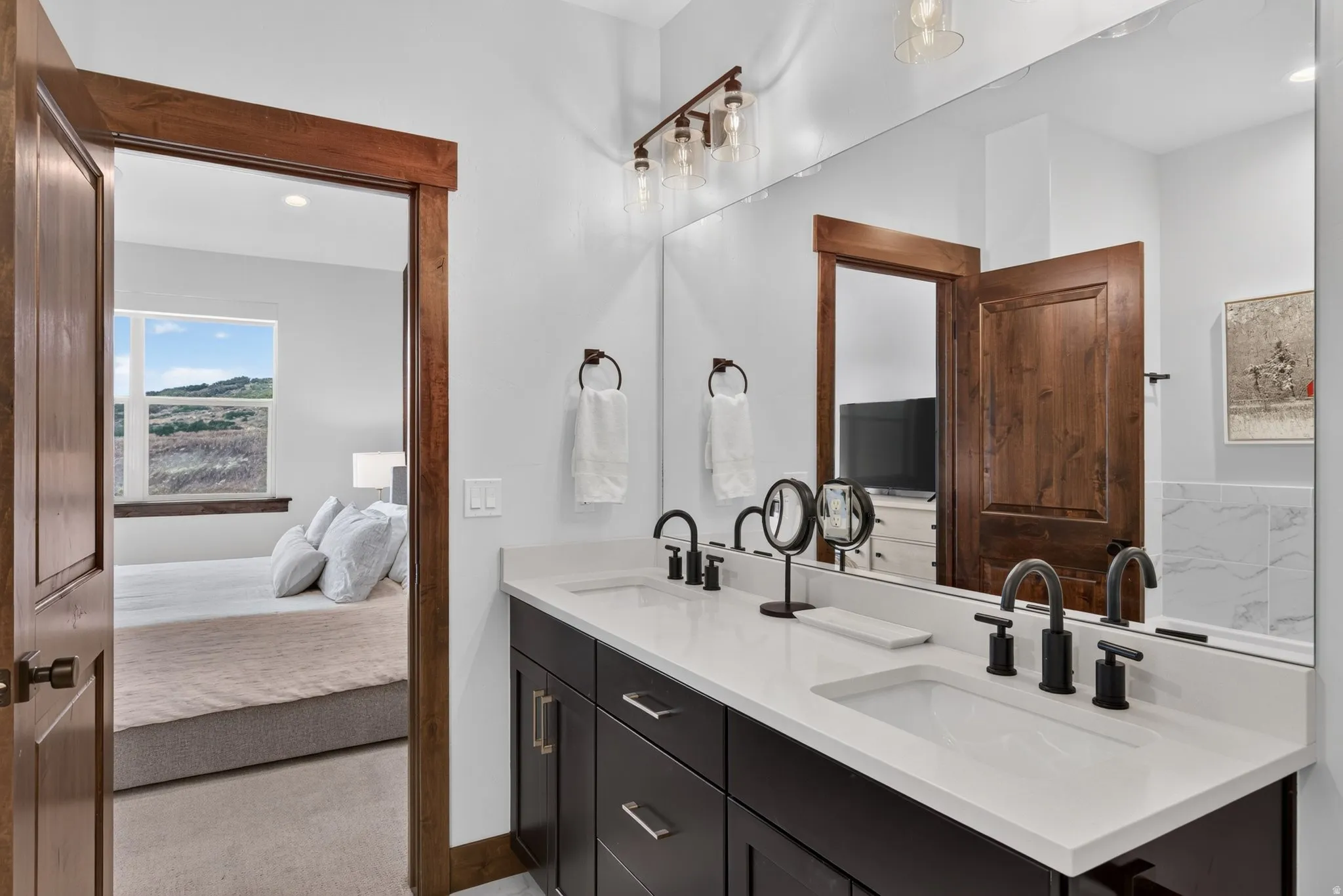 Dual vanity with dark wood-finish cabinetry, white countertops, and matte black fixtures
