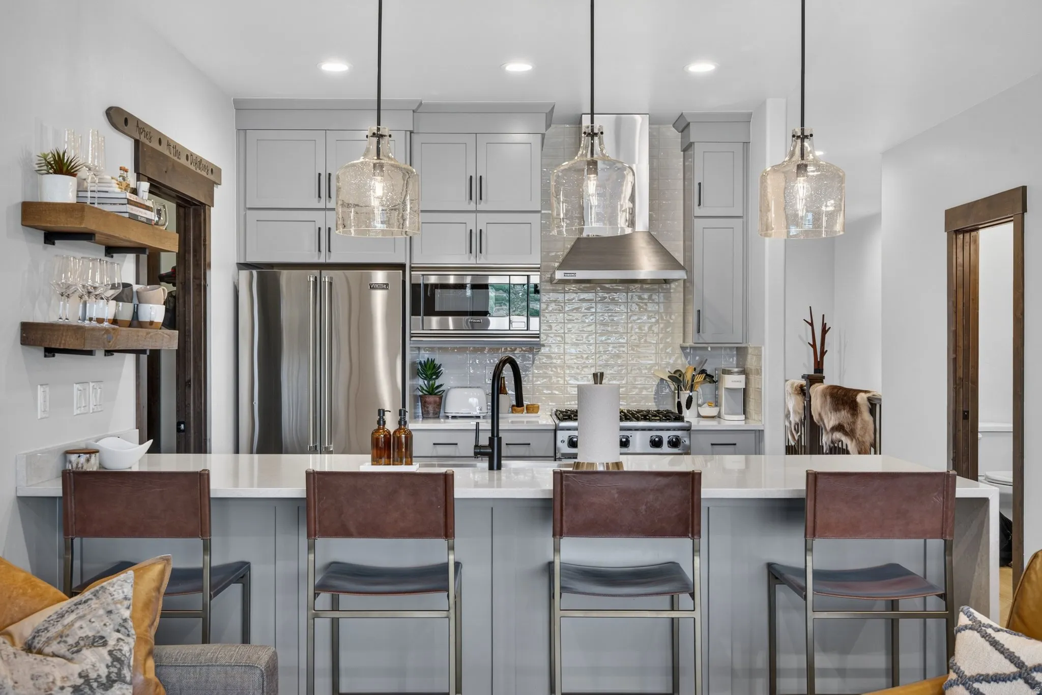 Kitchen featuring stainless steel appliances, light gray cabinetry, a white countertop, and three pendant light fixtures