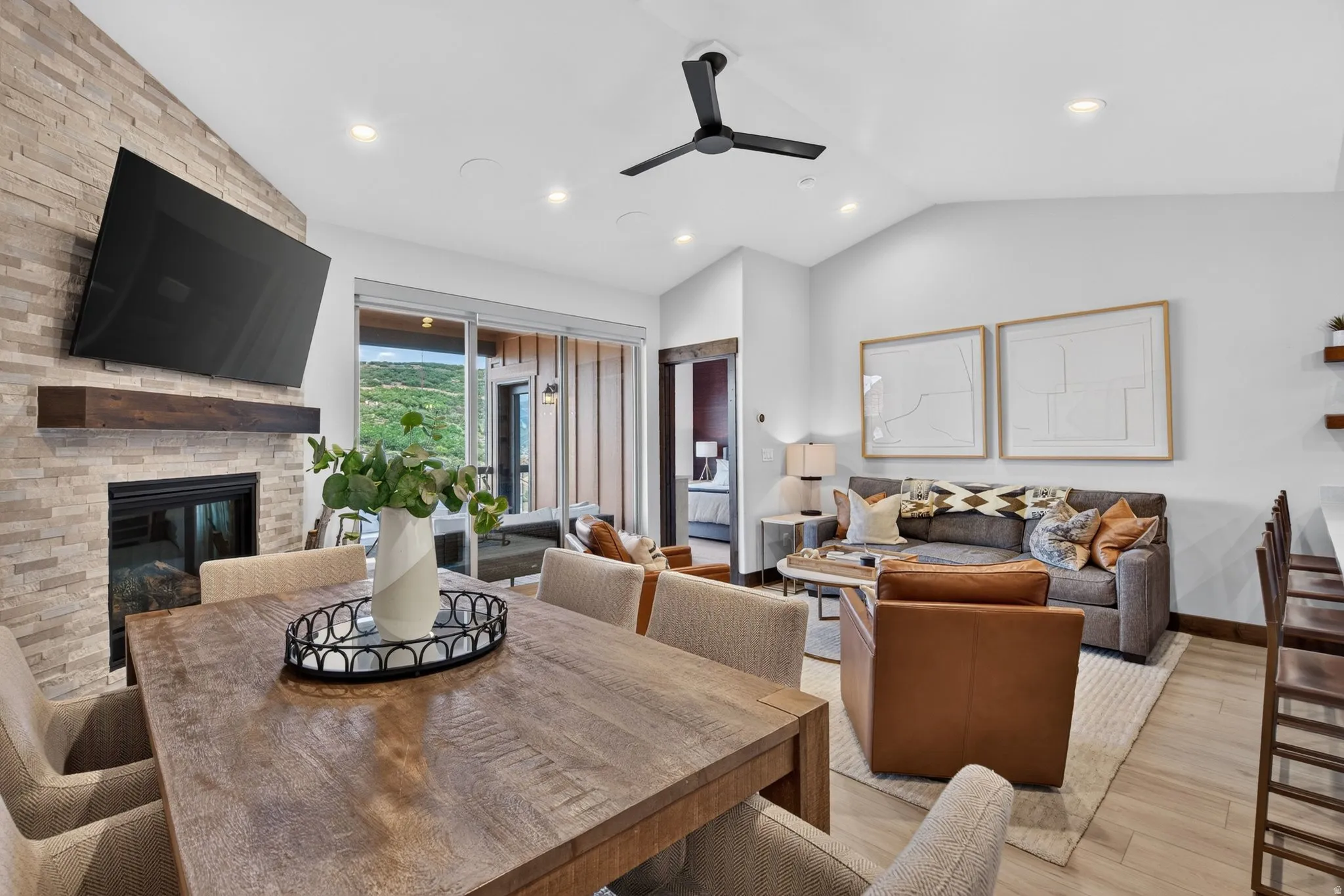 Stone-clad fireplace with a dark wood mantle, wood-finish flooring, recessed lighting, and a modern ceiling fan