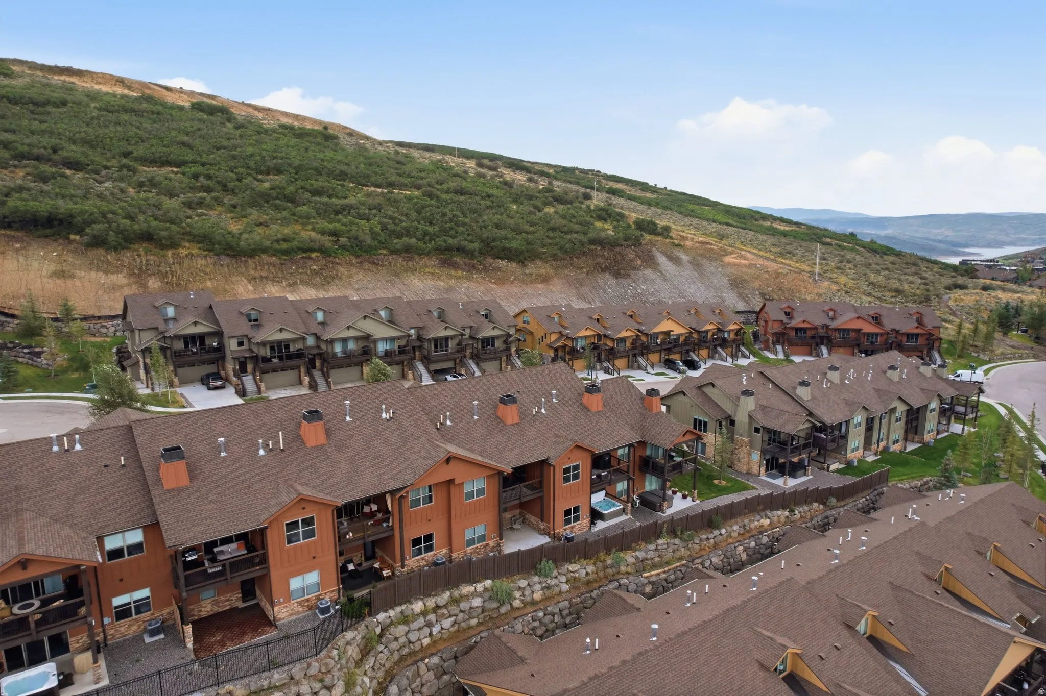 Terraced multi-story residences with attached garages, individual balconies, and stone retaining walls