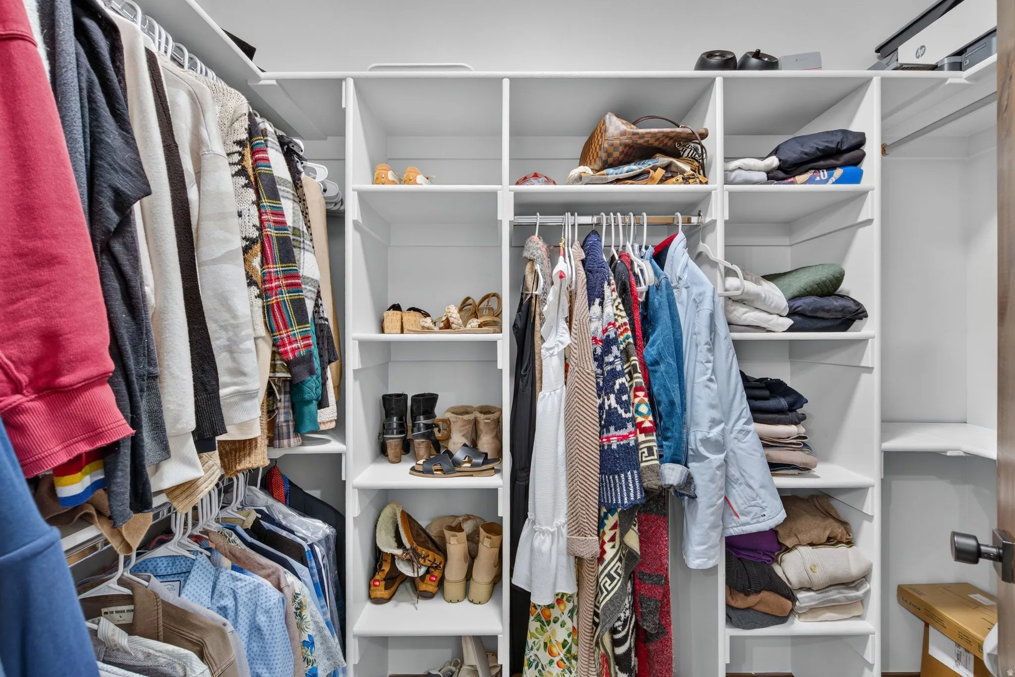 Integrated custom closet system featuring white shelving and multiple hanging rods
