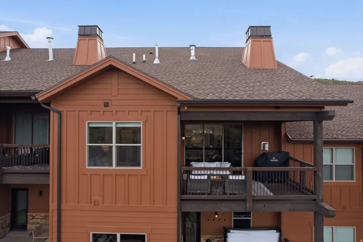 Multi-level exterior with board and batten siding, composite shingle roofing, and two prominent chimney structures