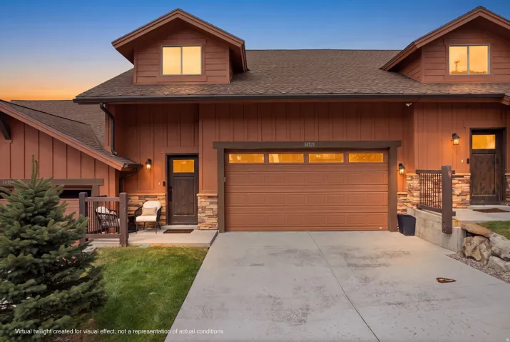 Two-story exterior with dormer windows, attached garage, and stone facade accents