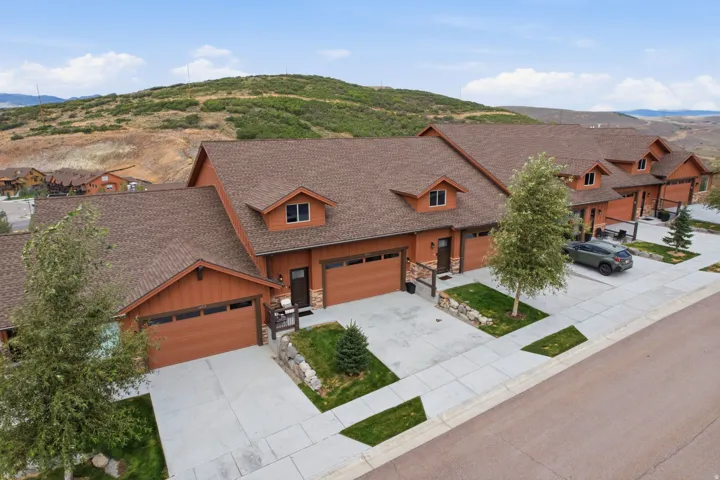 Townhome community featuring brown siding, attached garages, paved driveways, and front landscaping