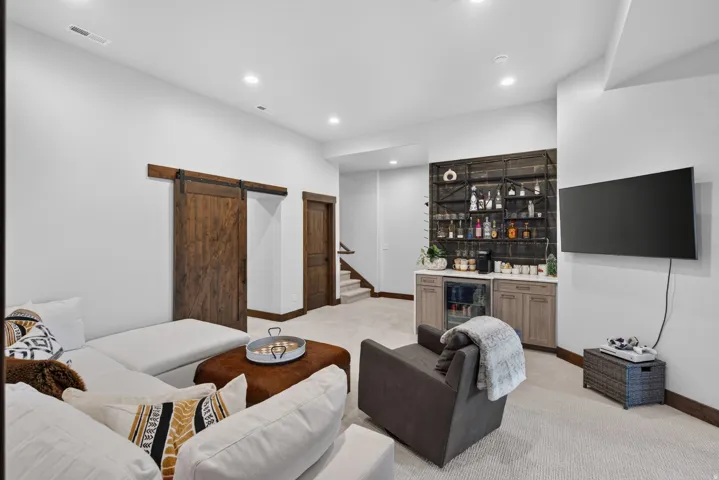 Built-in wet bar with wood-finish cabinetry, integrated beverage refrigerator, and open shelving