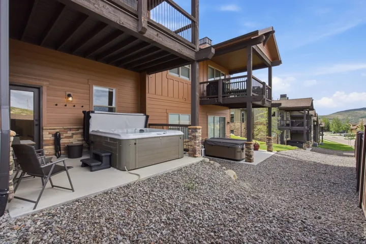Private patio featuring a built-in hot tub, durable concrete pad, and accent stone wall
