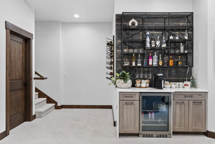 Built-in wet bar featuring a beverage refrigerator, wood-finish cabinetry, and a quartz countertop