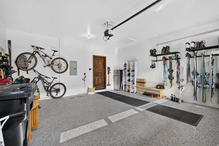 Garage with light gray epoxy flooring, white walls, and a wooden entry door