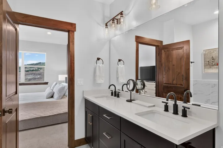 Dual vanity with dark wood-finish cabinetry, white countertops, and matte black fixtures