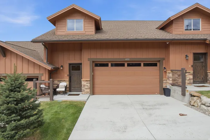 Exterior featuring board and batten siding, stone accents, and an attached garage with transom windows
