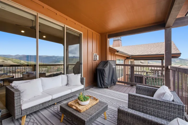 Covered outdoor patio with a durable wood-finish deck, brown wood siding, and ceiling-mounted lighting