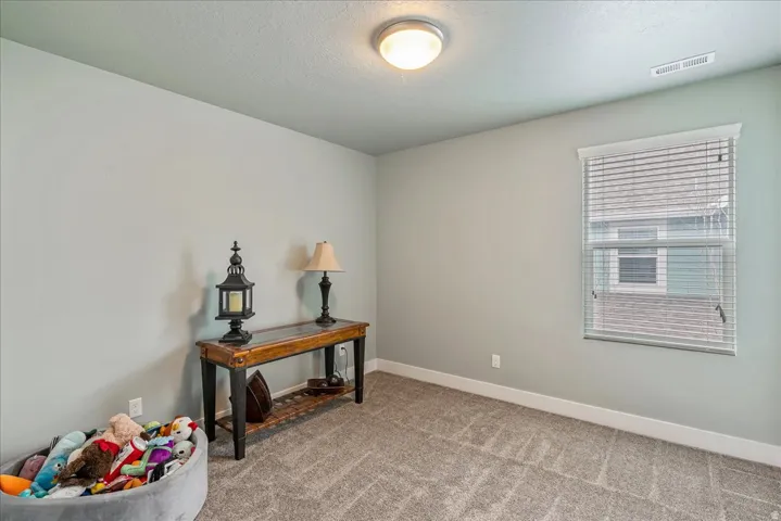 Carpeted flooring, light-toned walls, and a single window with blinds