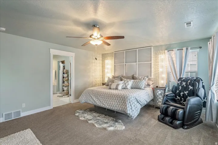 Carpeted room with a ceiling fan light fixture, textured walls, and a window with blinds