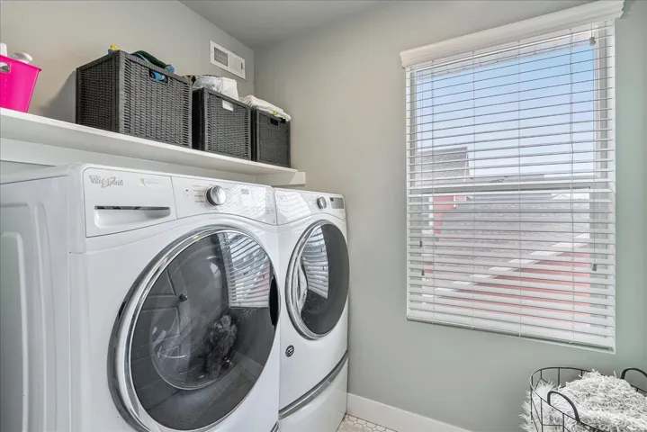 Laundry area featuring a window with horizontal blinds, a white floating shelf, and light-toned wall paint