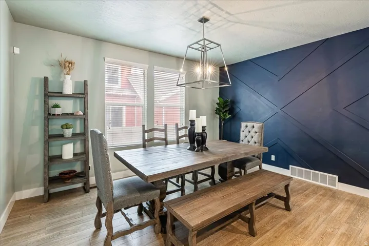 Feature wall with geometric paneling, wood-finish flooring, two window openings, and an overhead pendant light fixture