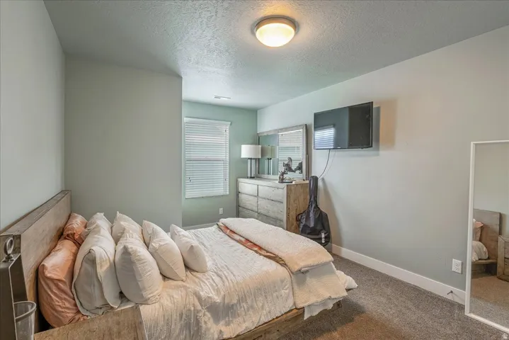 Carpeted flooring, window with blinds, flush mount ceiling light, and light-toned walls