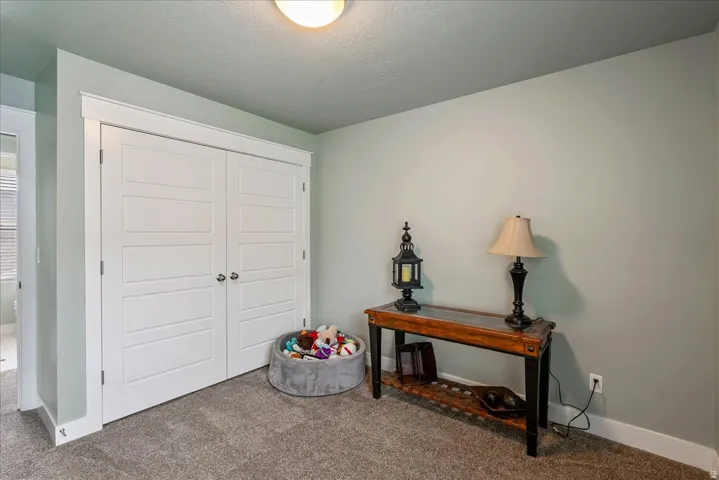 Built-in double closet with panel doors, neutral wall paint, and textured carpeting