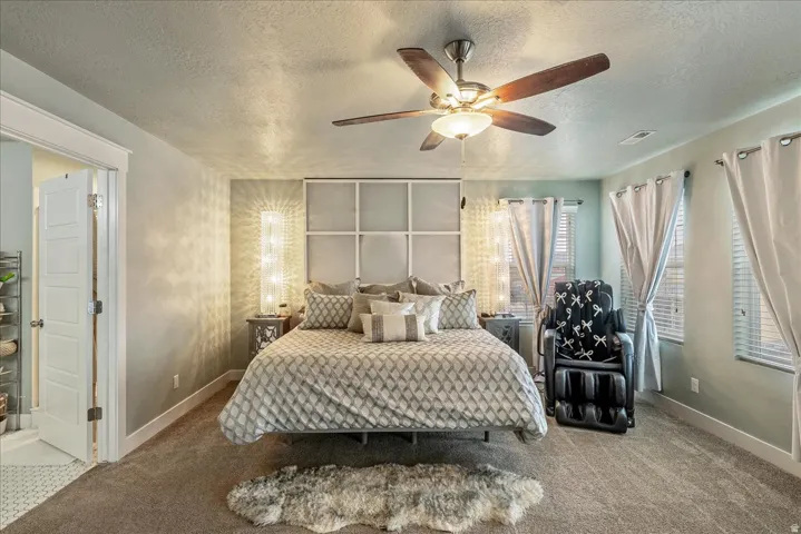 Ceiling fan with integrated lighting, wall-mounted light fixtures, multiple windows with blinds, and paneled interior door