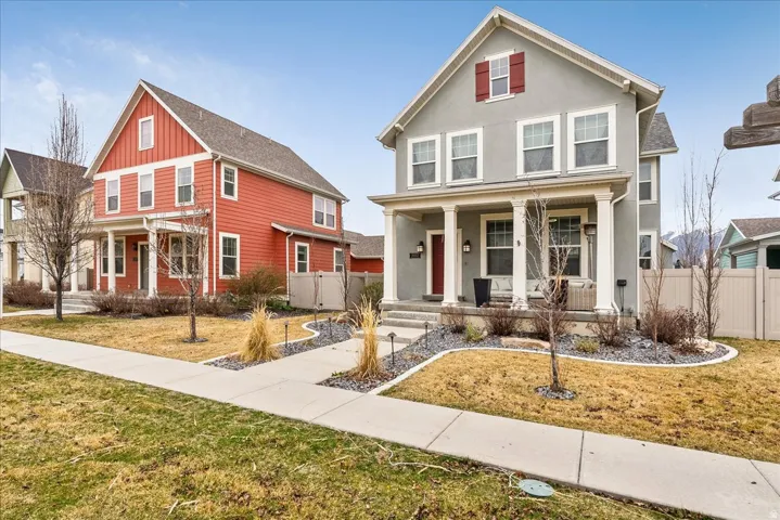 Stucco exterior with a covered porch, column accents, and red window shutters