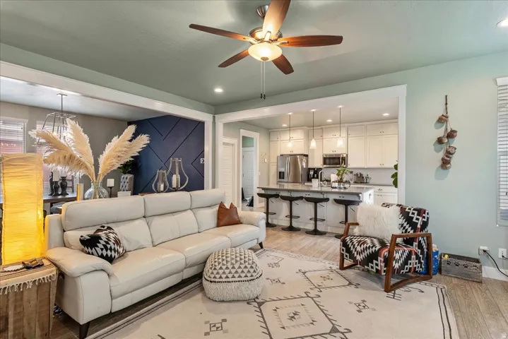 Open-concept living area with wood-finish flooring, a ceiling fan, and recessed lighting