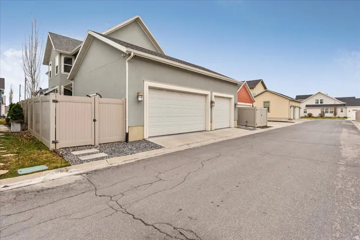 Two-car garage with overhead doors, stucco exterior, privacy fencing, and stone pathway