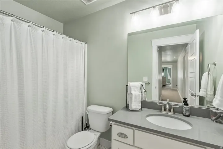 Vanity with a gray countertop, an oval undermount sink, and brushed nickel fixtures