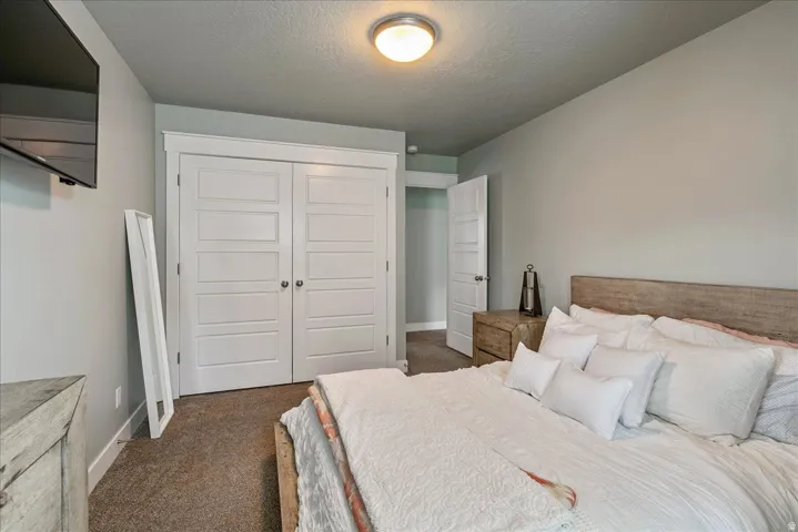 Spacious primary bedroom featuring a wood-finish headboard, generous bed dimensions, and abundant natural light from recessed ceiling fixture