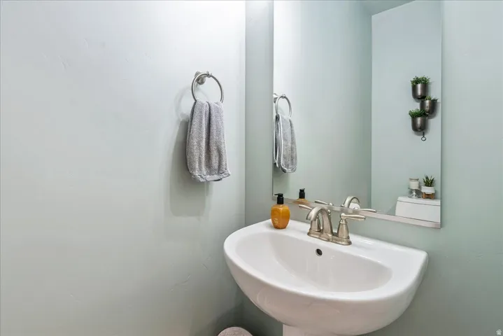 Pedestal sink with a polished chrome faucet, full-height mirror, and wall-mounted towel ring