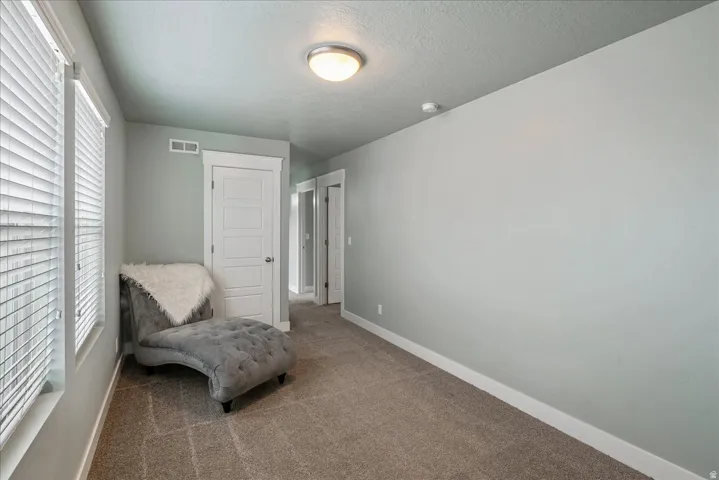 Carpeted flooring, white trim, recessed lighting, and multiple windows with blinds