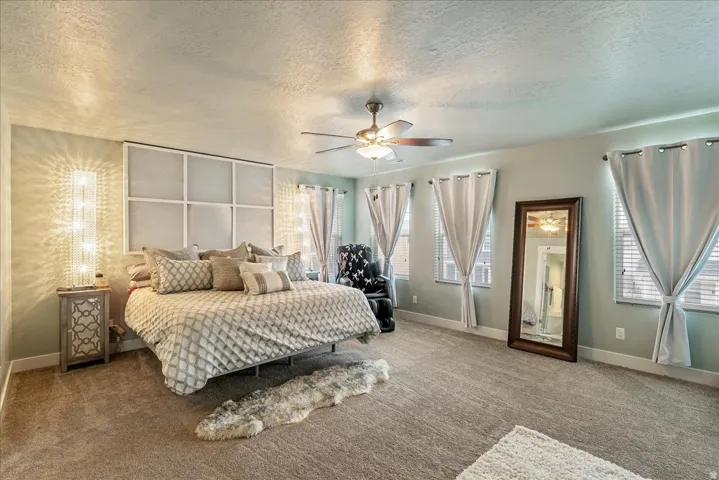 Built-in ceiling fan with integrated lighting, wall-mounted light fixtures, textured wall paneling, and multiple windows