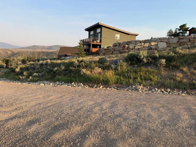 Multi-level residence featuring a wood deck and a stone retaining wall