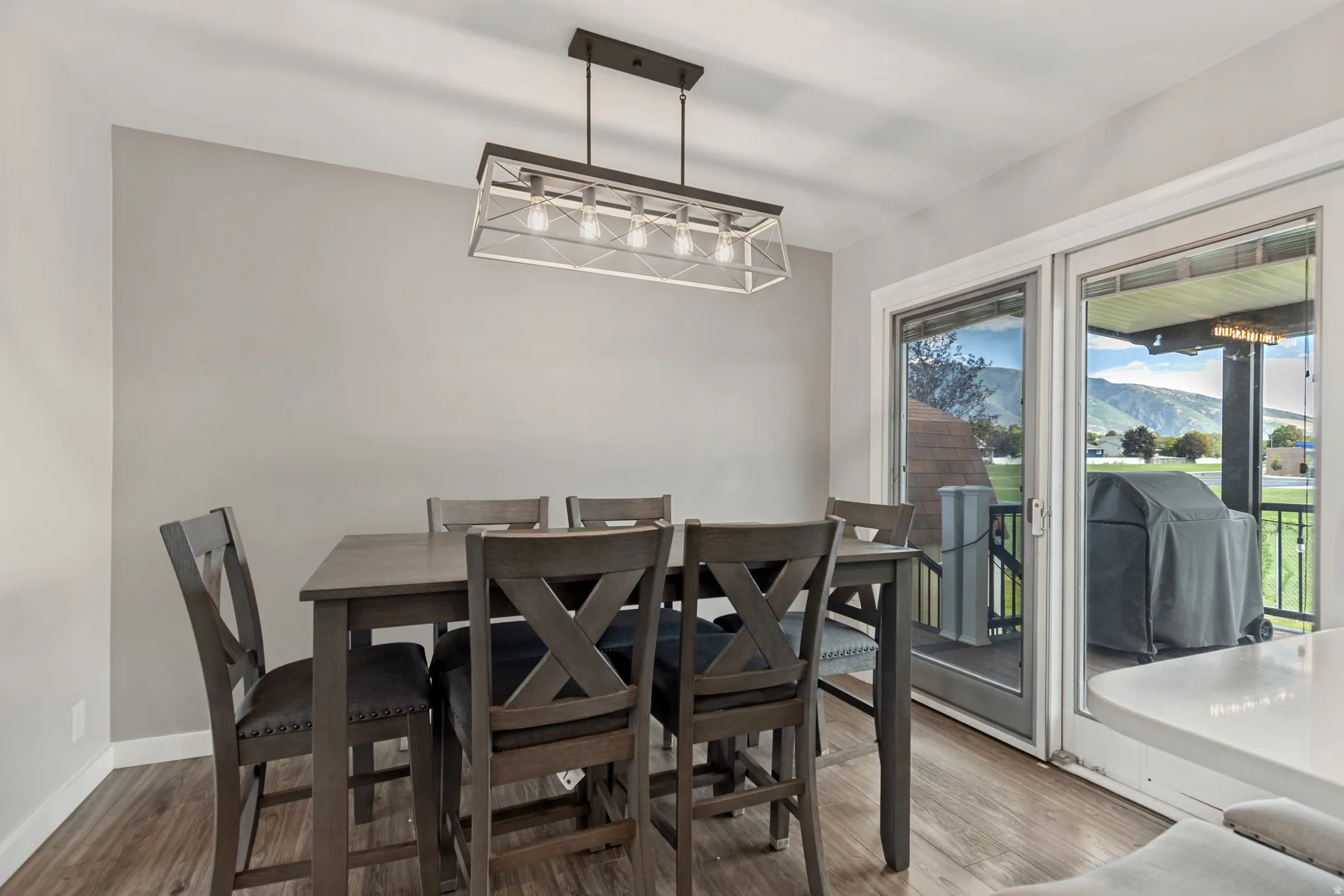 Wood-finish flooring with a modern linear chandelier, light gray walls, and white trim